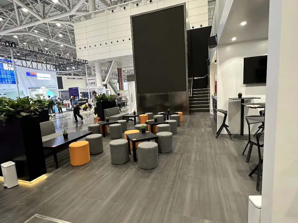 Seating area with orange and grey stools, wall screen and stairs behind