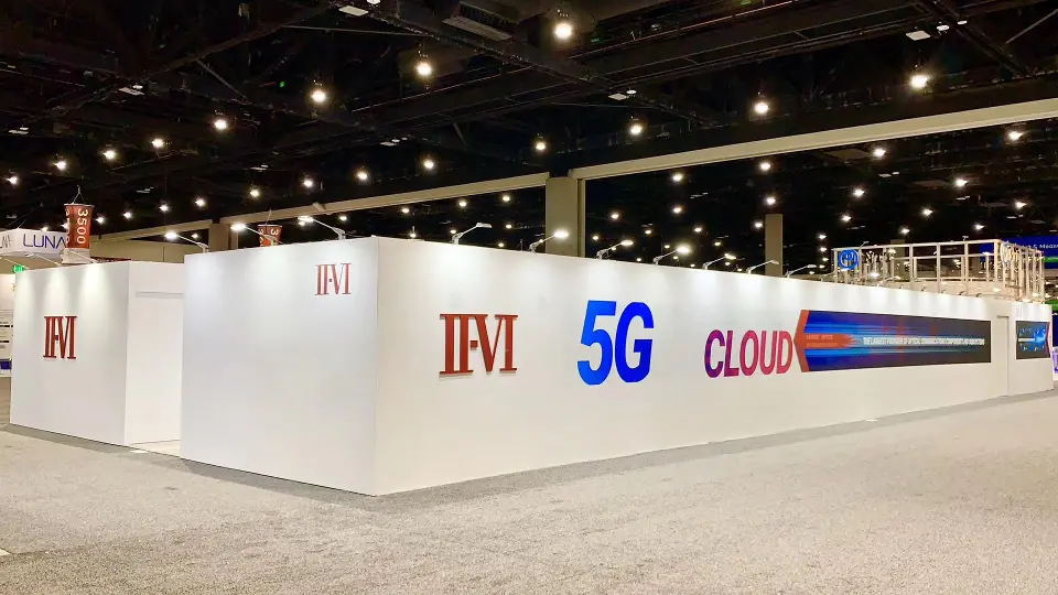 Long white wall with II-VI, 5G and CLOUD lettering on grey carpet