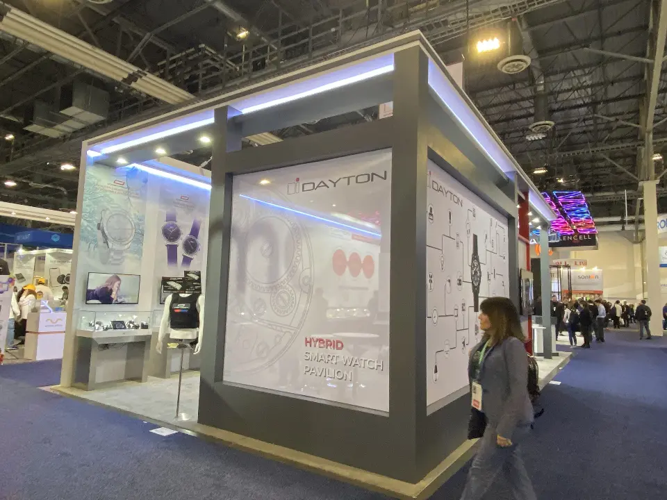 Booth corner from the aisle showing light-edged frame and glass showcases