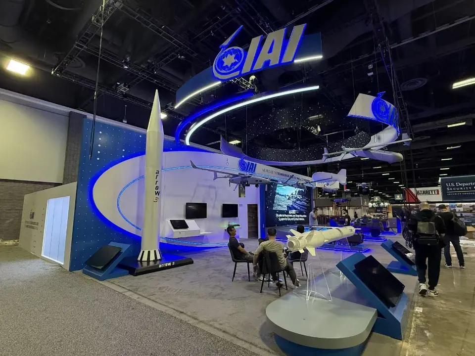 Wide view of the IAI stand with meeting tables, missile models and suspended curves