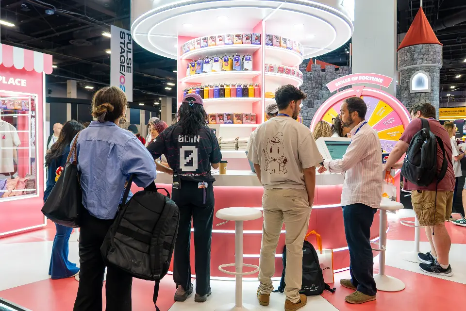 Attendees lined up at the AIR merch counter in front of the lit shelf tower and the prize wheel