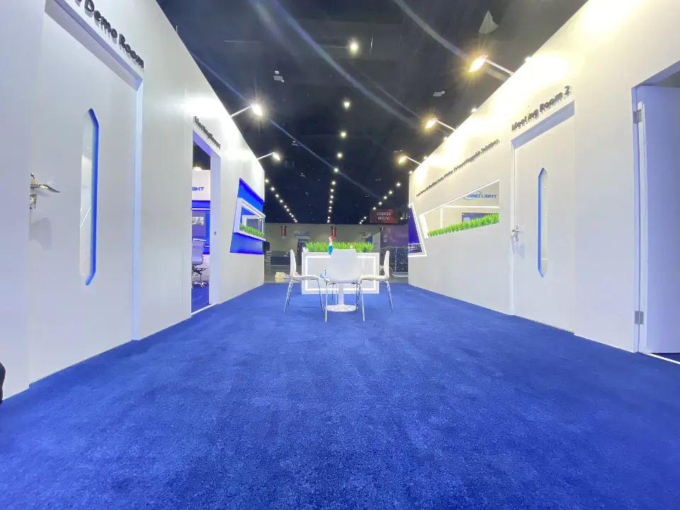 Interior aisle between white rooms with blue carpet and wall graphics