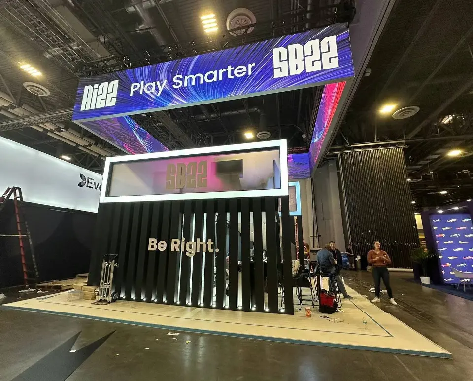 Front of the booth with Play Smarter header, black slatted wall and lit white frames