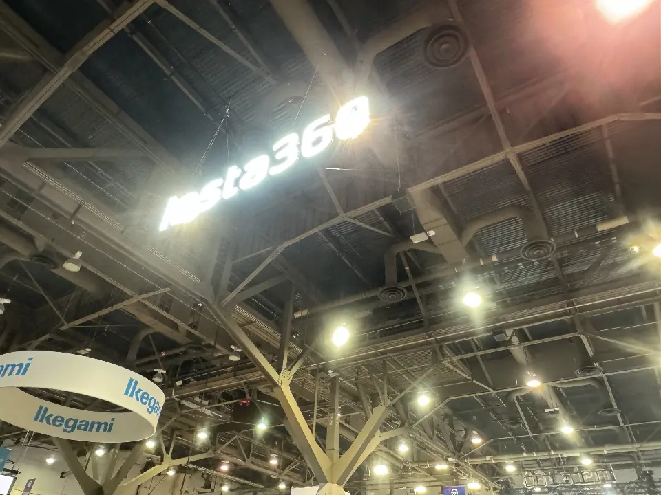 Lit Insta360 lettering suspended high above the booth under the hall roof