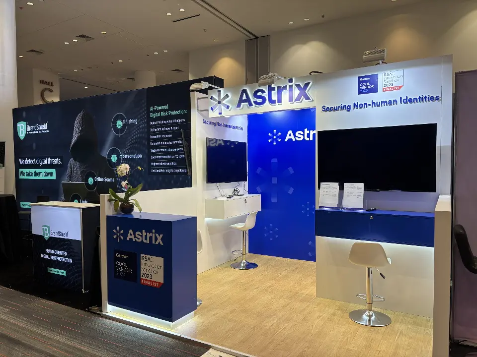 Angled view of the Astrix booth with large screen, white counter shelf and wood-look floor