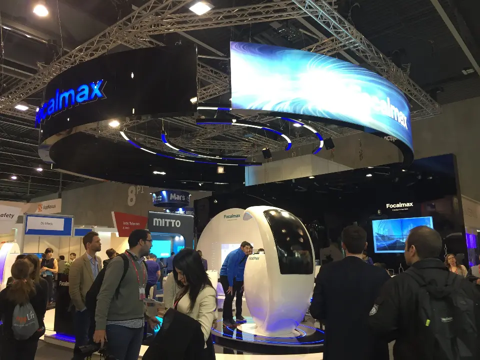Visitors passing the stand with the curved blue header and white egg kiosks