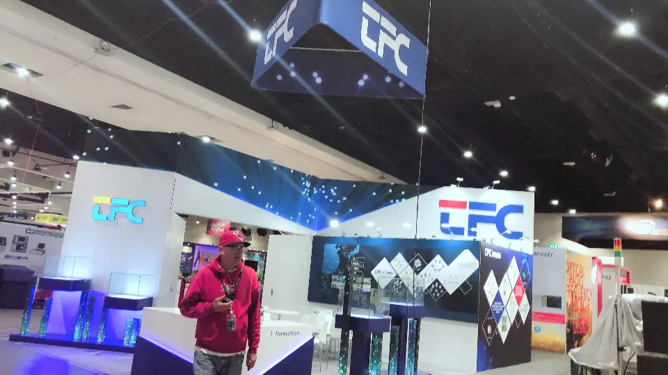 Visitor beside lit glass product cases under the TFC fascia and hanging sign