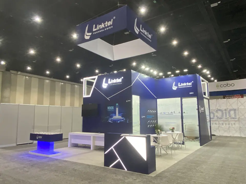 Corner view of Linktel navy booth with square hanging sign and blue-lit counter base