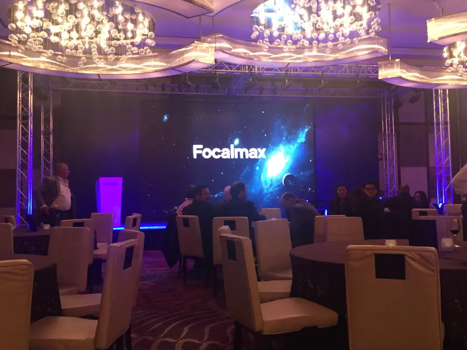 Wide ballroom shot of guests at tables with the glowing Focalmax screen
