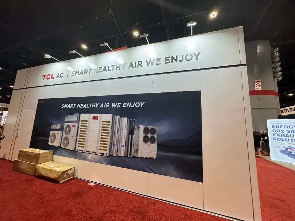 Long white TCL AC wall with air conditioner graphic and crates on red carpet