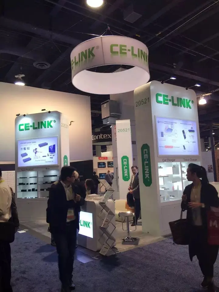 Vertical view of the white booth with green CE-LINK hanging ring and lit wall towers