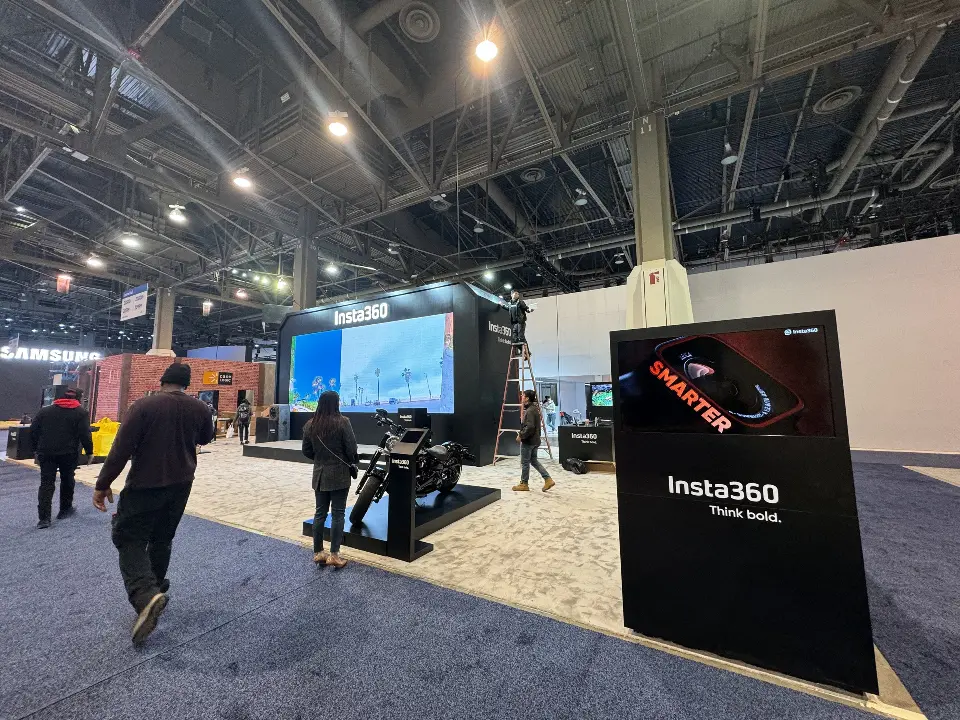 Aisle view with a dark Insta360 sign panel near the booth edge