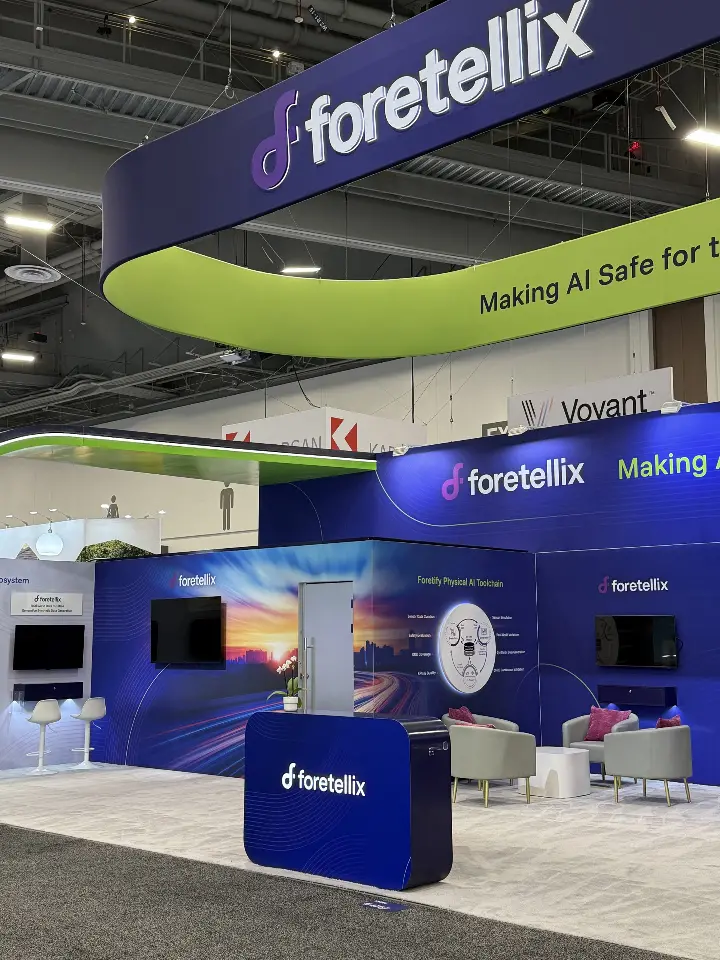 Front of the Foretellix booth with navy counter under the curved lime-green overhead ring