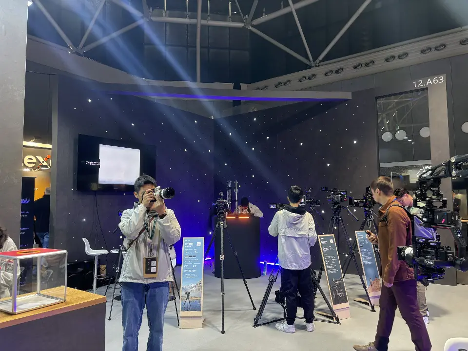 Camera rigs on stands under spotlights with a wall screen behind