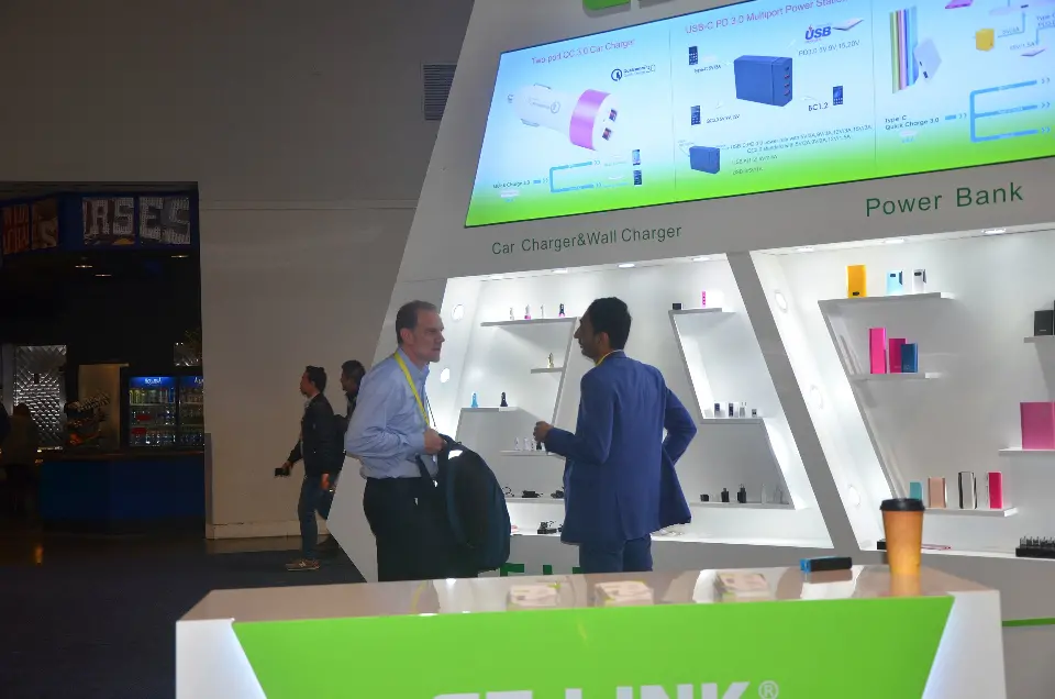 Visitors at the backlit display wall showing power bank products