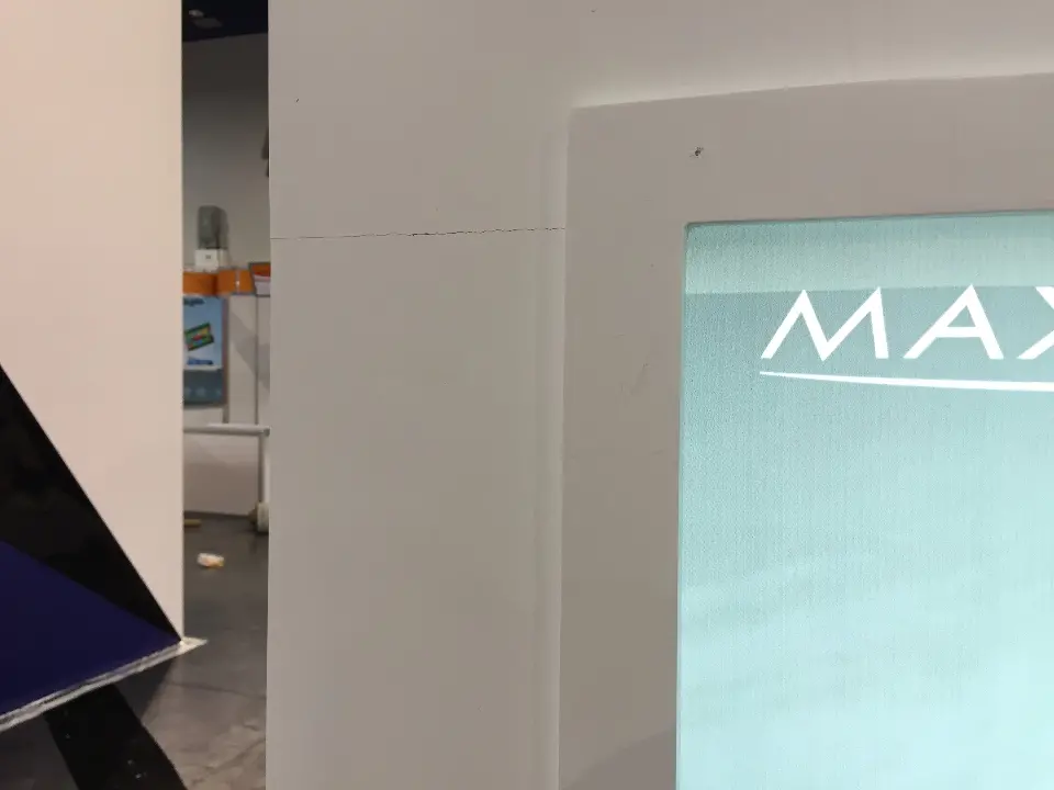 Corner detail of a white panel beside a backlit MAXCO graphic