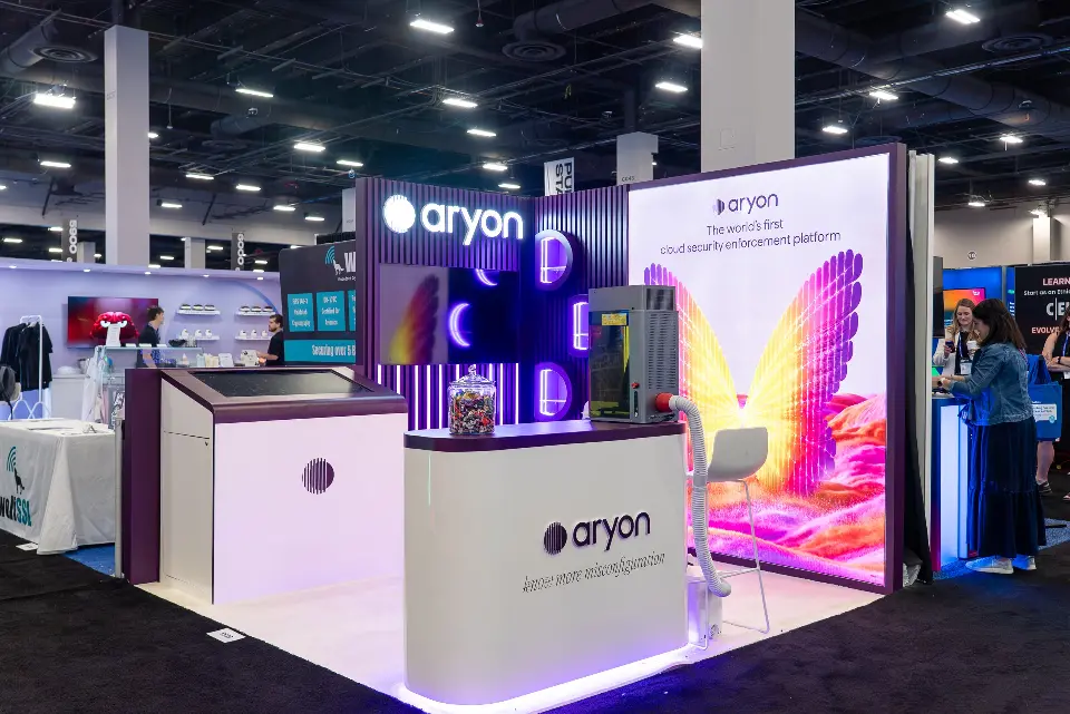 Finished Aryon booth with lit logo on a purple slat wall and the butterfly-wing graphic