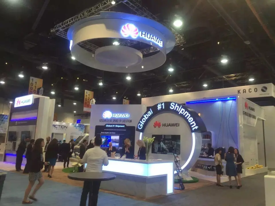 Circular HUAWEI hanging sign above a white counter and curved wall graphic