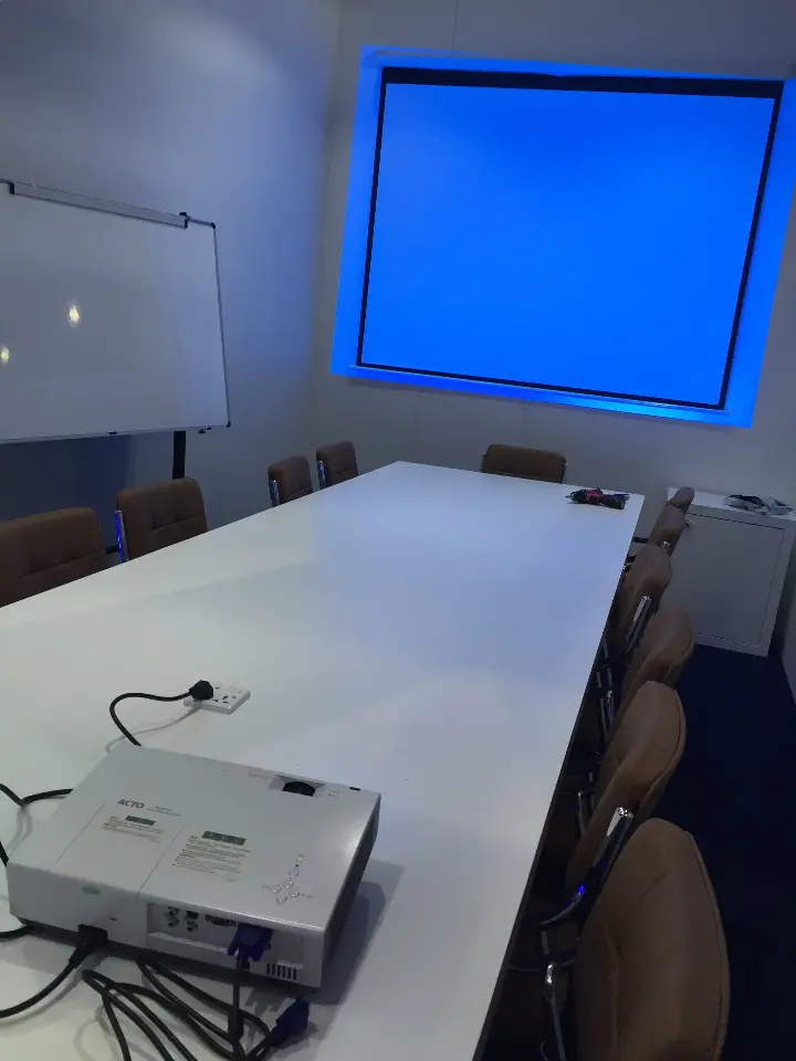 Meeting room with white table, chairs, projector and a blue projection screen
