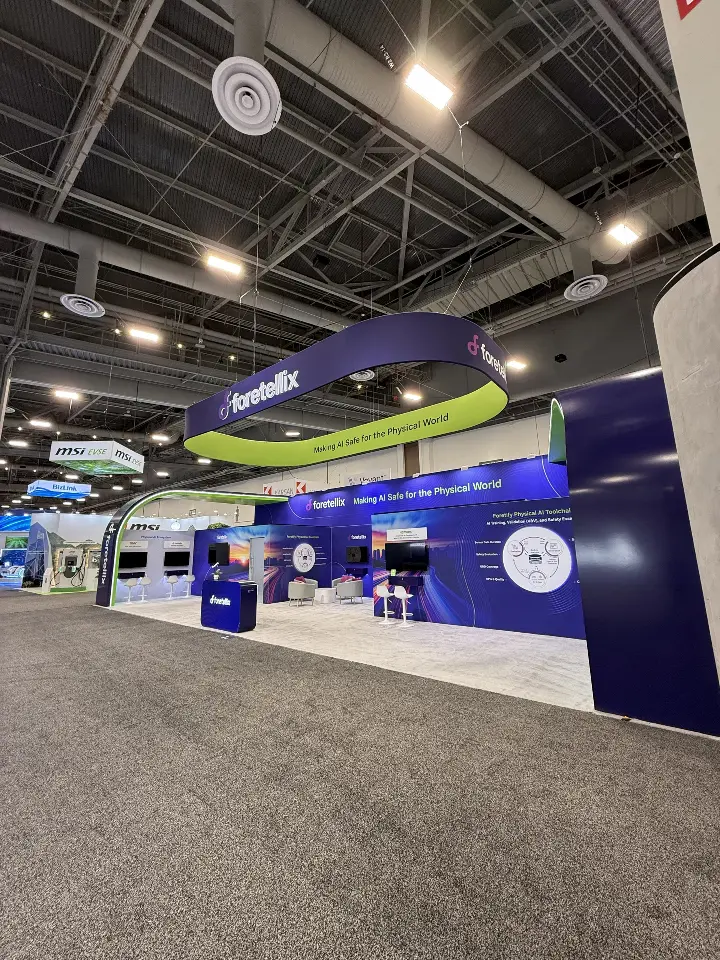 Corner aisle view of the Foretellix island booth with the hanging ring above