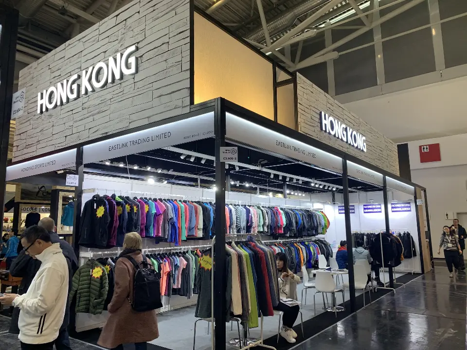 Racks of colorful jackets and apparel inside booths beneath the HONG KONG fascia