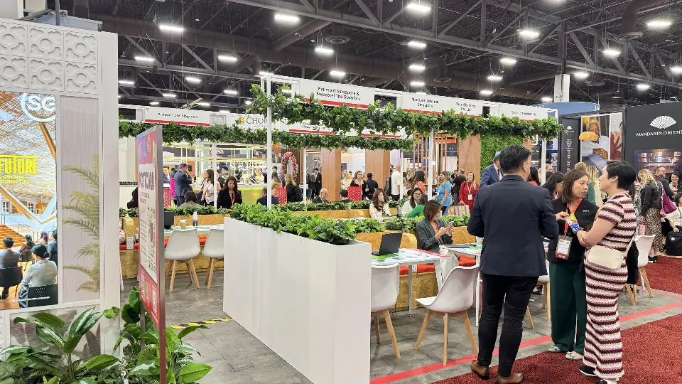 Meeting tables with white chairs behind tall planters filled with leafy plants