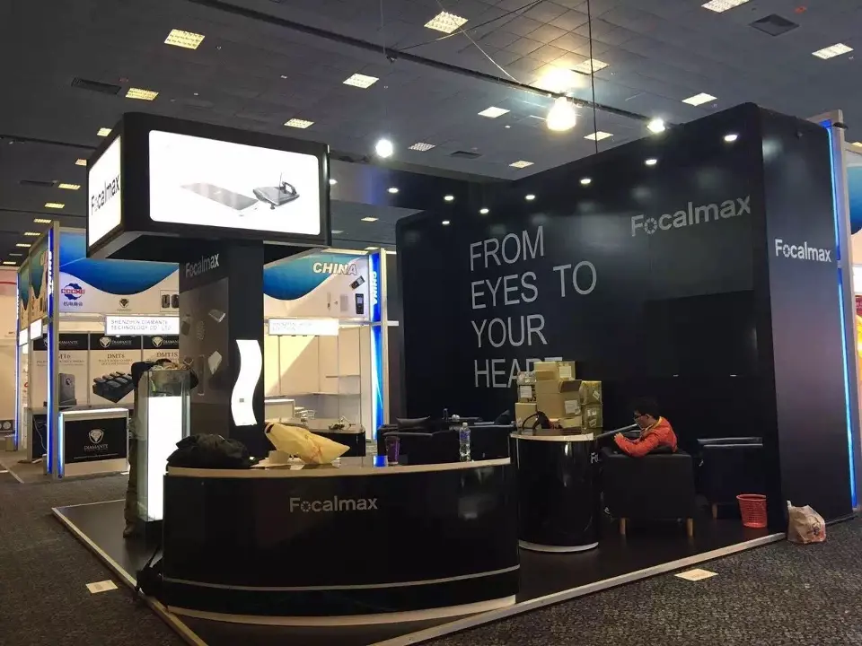 Corner view of the black Focalmax booth with FROM EYES TO YOUR HEART wall and lightbox header