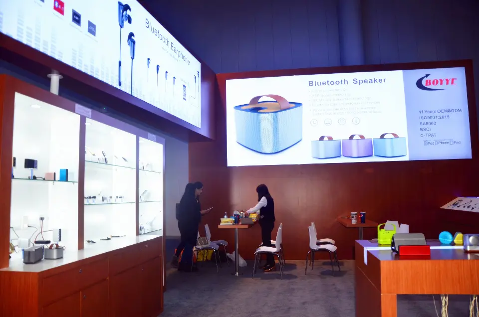 Bright backlit speaker graphic over shelving with staff at a table