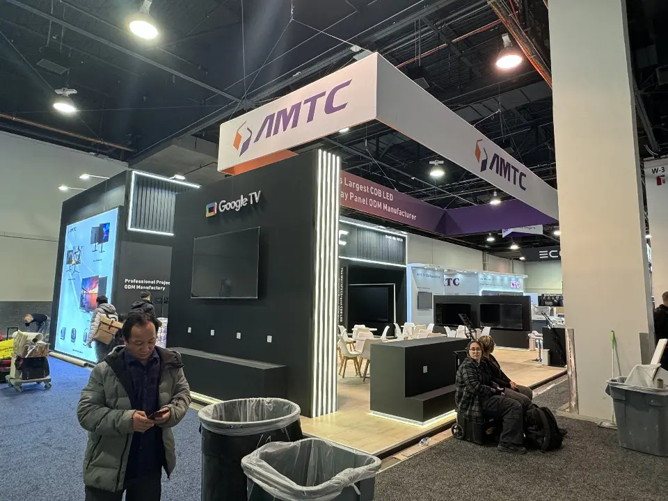 AMTC booth side with Google TV screen wall and purple header above