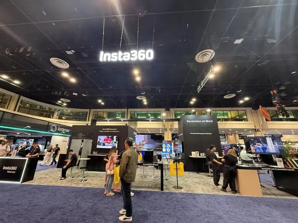 Black Insta360 booth with suspended lit sign above product counters and screens