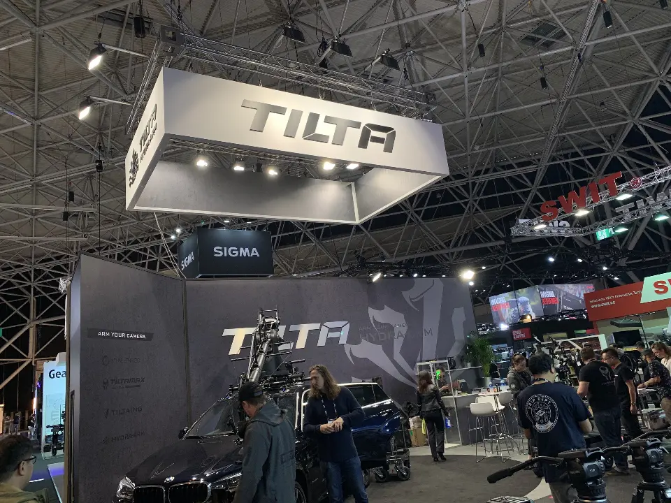 Tilta booth with white square hanging sign, grey graphic wall and camera rigs