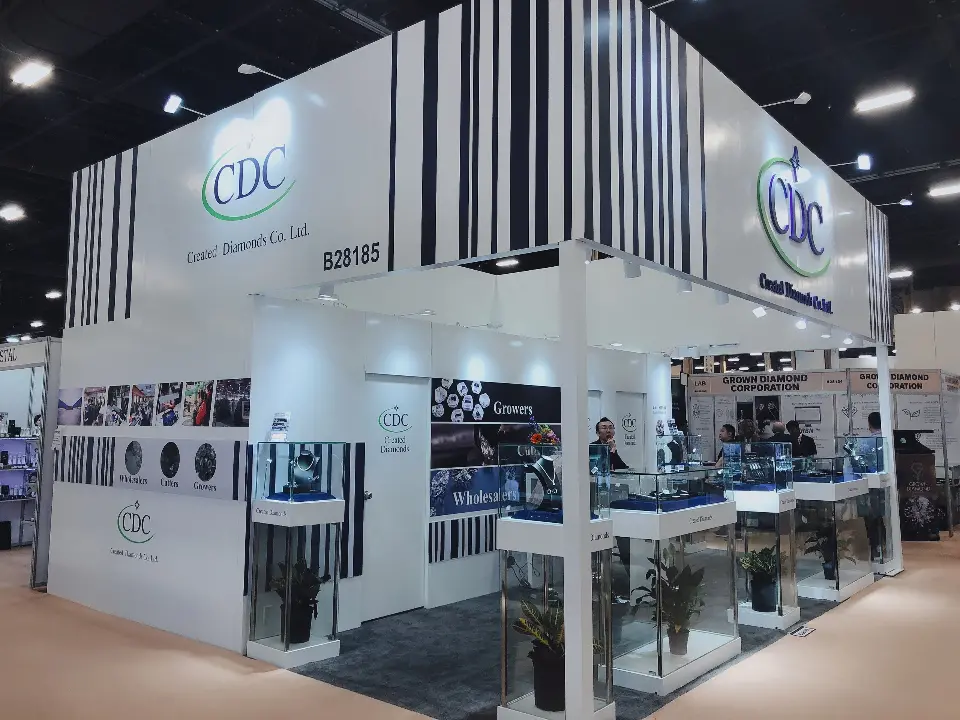 Corner view of the white CDC booth with stripe header, showcases and potted plants