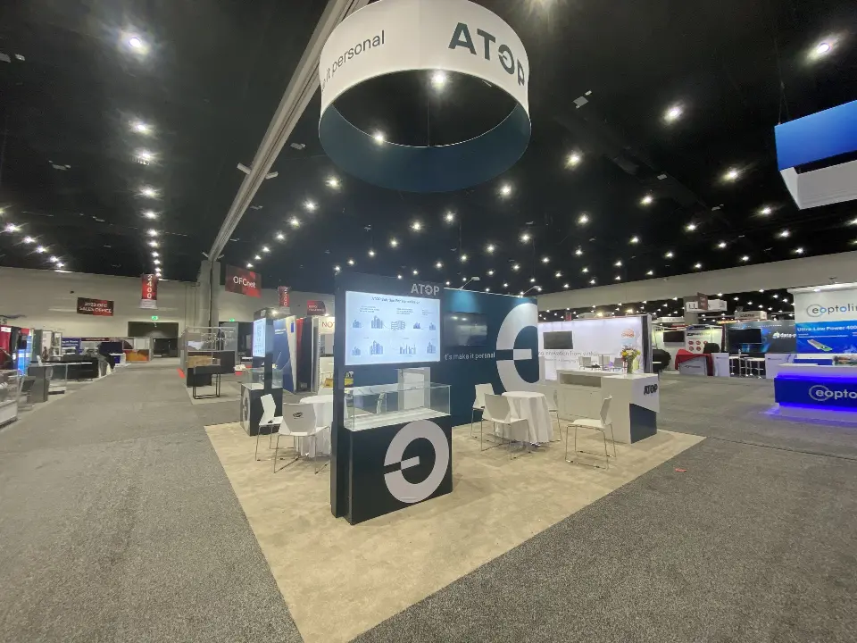 Visitors walking past the booth with screen tower and teal wall behind