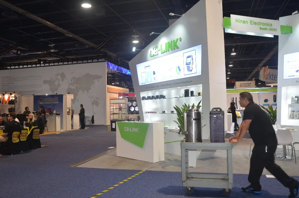 Staff wheeling a cart past the finished booth, plant and counter
