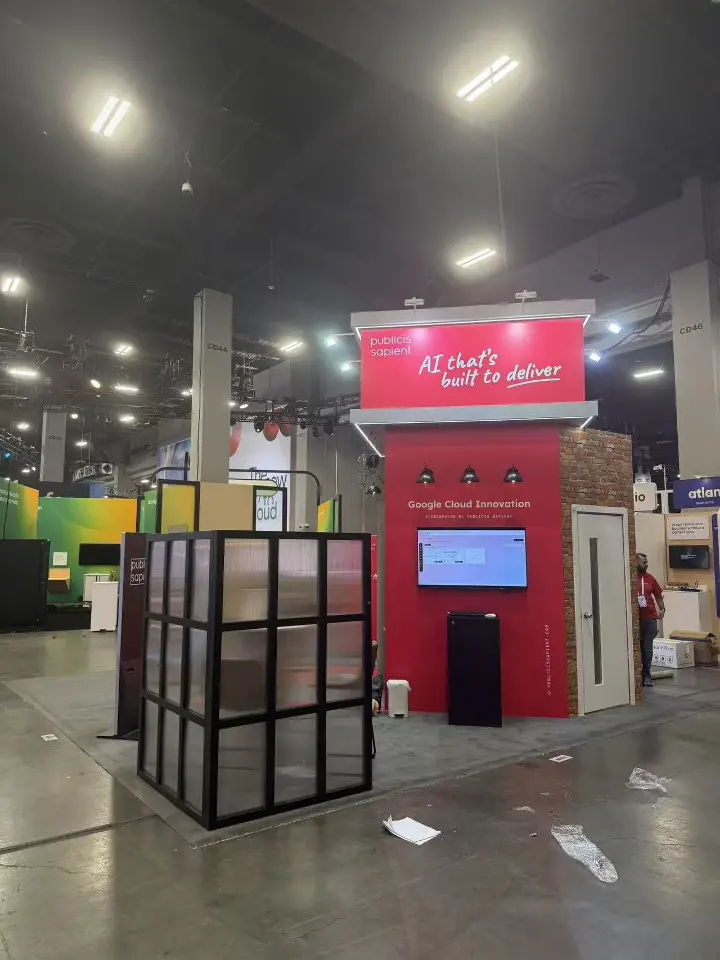 Red Google Cloud Innovation wall with pendant lamps, screen, black kiosk and grid cube
