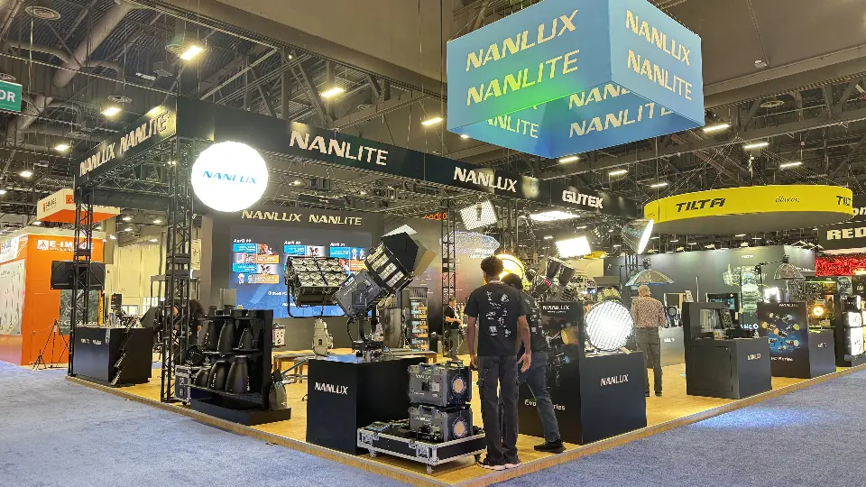 Front of the Nanlux and Nanlite stand with fixtures on cases, lit counters and the blue cube banner
