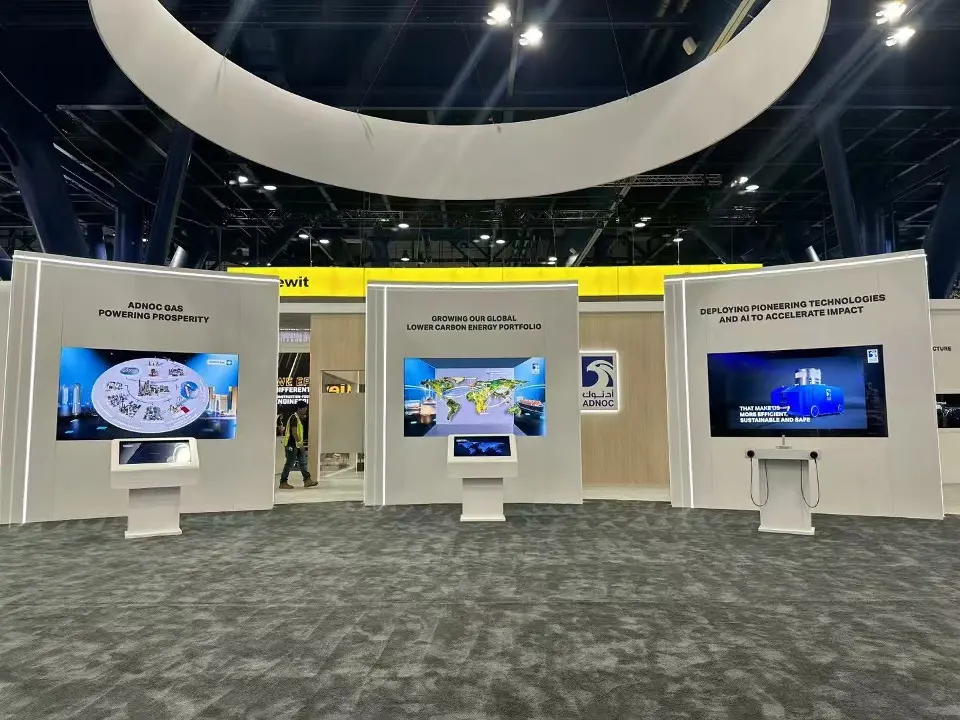Curved row of white display walls with screens under the hanging ring