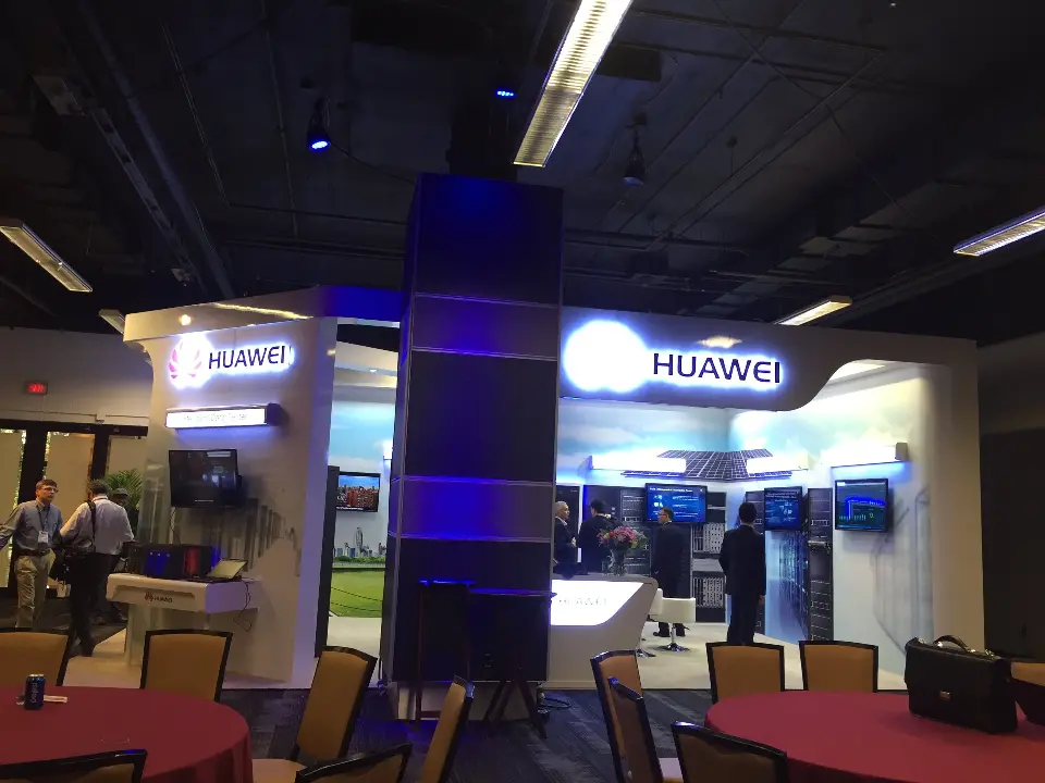 Wide view of the Huawei booth with visitors and round tables in the foreground