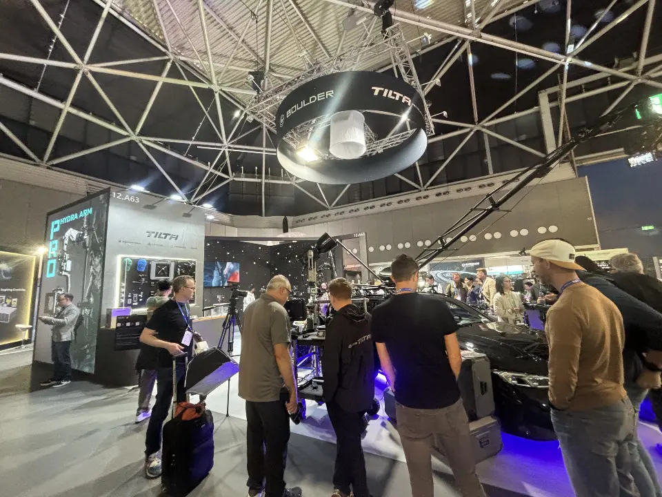 Visitors at display tables under the ring sign and spotlights