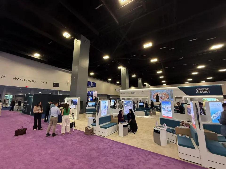 Front of the booth with teal pods, lit columns and visitors at tables
