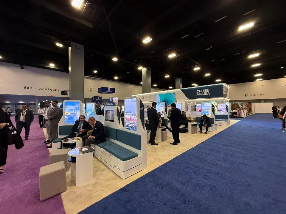 Guests walking past meeting pods and backlit columns along the purple aisle