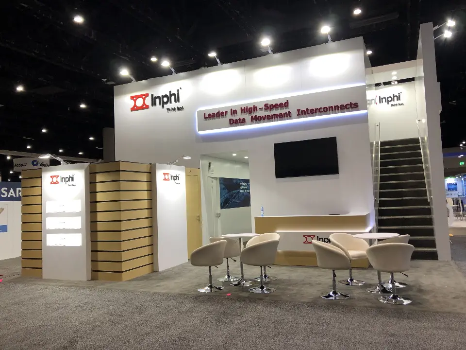 Finished Inphi booth with white lounge chairs, wall screen and black staircase