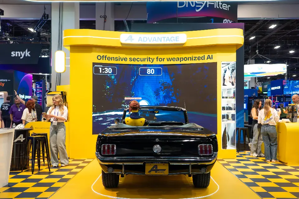 Advantage booth at Black Hat USA 2026 with a black convertible facing an LED driving game on a checkered floor