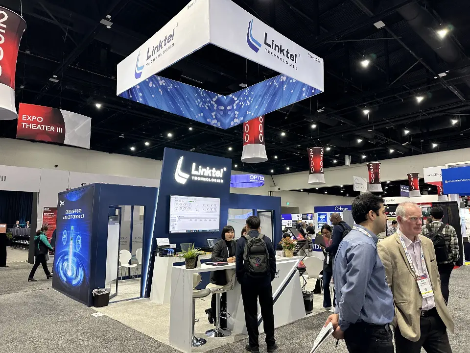 Linktel booth with square hanging sign, navy walls, lit logo and white counter with stools