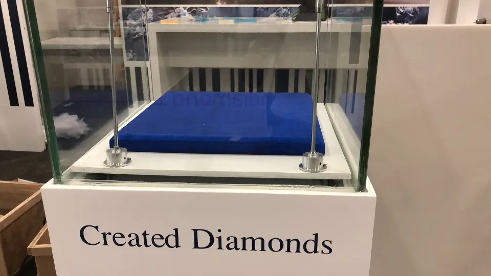 Showcase with blue velvet tray beside a plain white booth wall