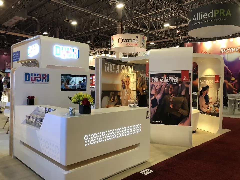 Reception counter with a patterned front below a glowing Dubai logo
