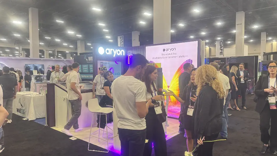 Visitors gather at the Aryon counter with the purple slat wall and lit logo above