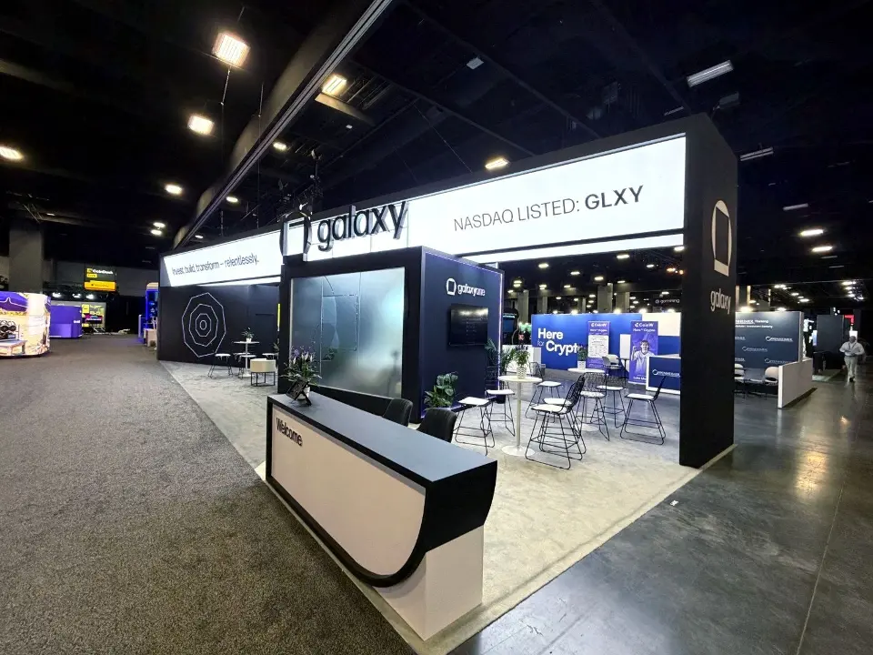 Curved white counter in front of a large screen at the booth corner