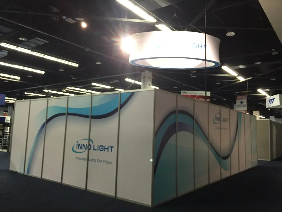 White booth walls with sweeping blue wave graphics under the round hanging sign