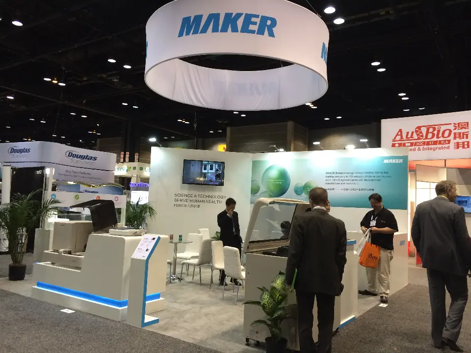 MAKER stand at AACC 2014 with large white hanging ring, analyzers on curved plinths and visitors